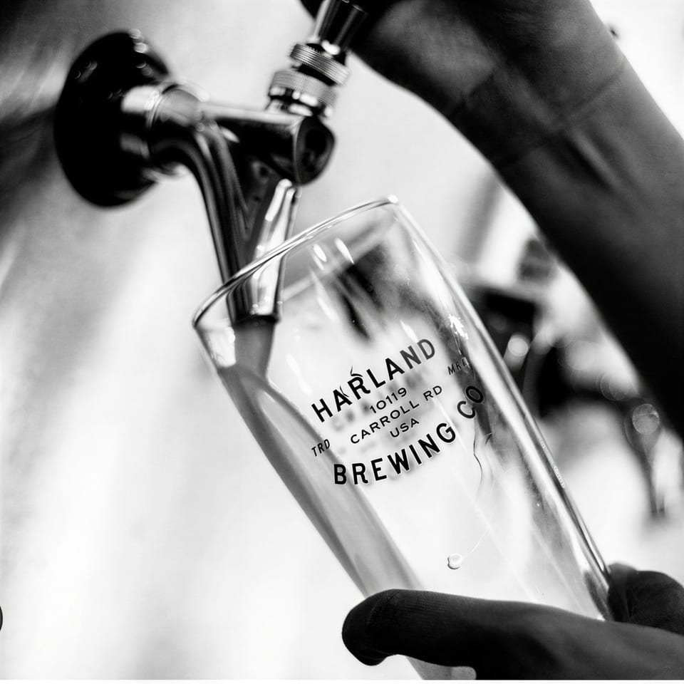 Black and white close-up of a Harland Brewing Co. glass being filled from a tap.